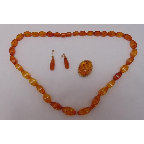 339 - 9ct gold and amber brooch, 9ct gold and amber earrings and an amber necklace