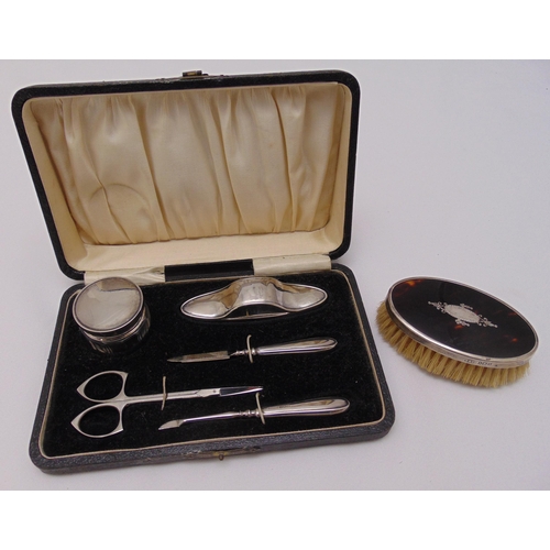 457 - A cased hallmarked silver manicure set to include a glass bottle with silver cover, a nail buff, a p... 