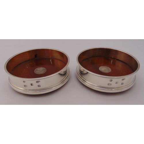 465 - A pair of hallmarked silver bottle coasters with turned wooden bases, 10cm (w)