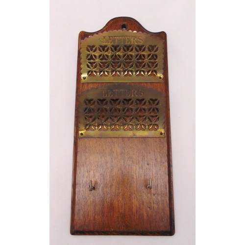 245 - An early 20th century oak rectangular wall hanging letter rack with pierced brass letter holders