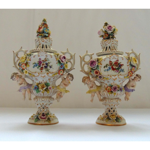 90 - A pair of Crown Naples vases and covers with twin foliate handles, putti figurines, flowers and leav... 