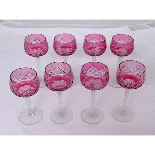 154 - Eight cranberry coloured cut glass hock glasses on raised circular bases