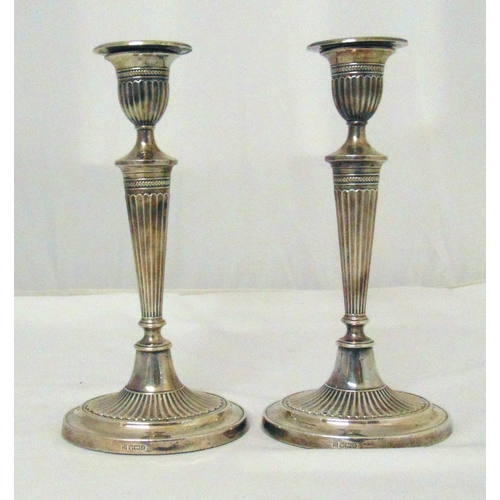 383 - A pair of Edwardian hallmarked silver candlesticks of oval neoclassical Adam design with tapered ree... 