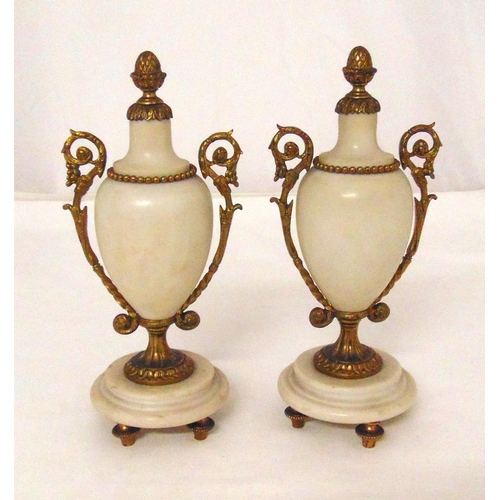 259 - A pair of late 19th century white marble clock garnitures on raised circular bases and four spool su... 