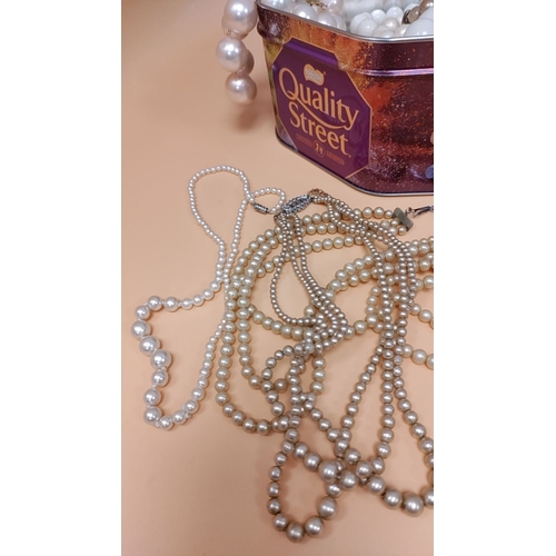 616 - Assorted costume jewellery in a Quality Street tin, featuring various beaded necklaces in faux pearl... 