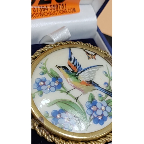 623 - LIMOGES France hand-painted enamel brooch features a colourful bird among blue floral motifs, encase... 