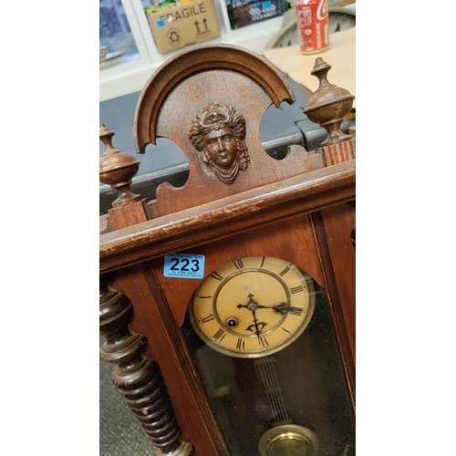 223 - Wooden Wall Clock with key, brass Pendulum and ornate top detailing