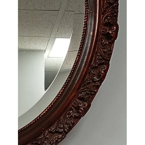 484 - Oval bevelled mirror in brown scrolled detail frame H 49cm x W 38cm