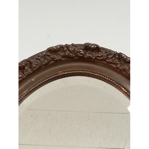 484 - Oval bevelled mirror in brown scrolled detail frame H 49cm x W 38cm