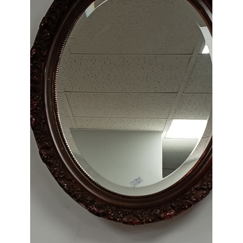 484 - Oval bevelled mirror in brown scrolled detail frame H 49cm x W 38cm