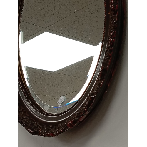 484 - Oval bevelled mirror in brown scrolled detail frame H 49cm x W 38cm