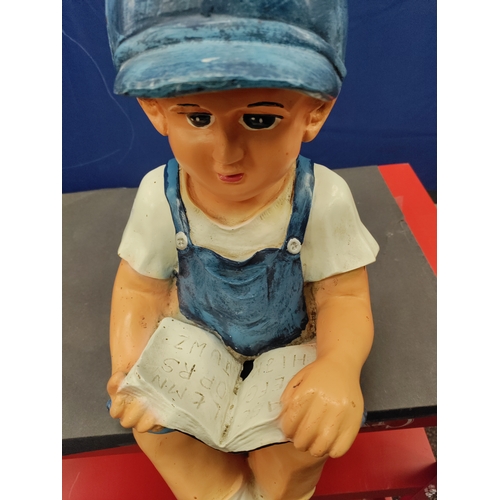 568 - A fiberglass figure of a boy sitting and reading a book H 44cm x W 24cm