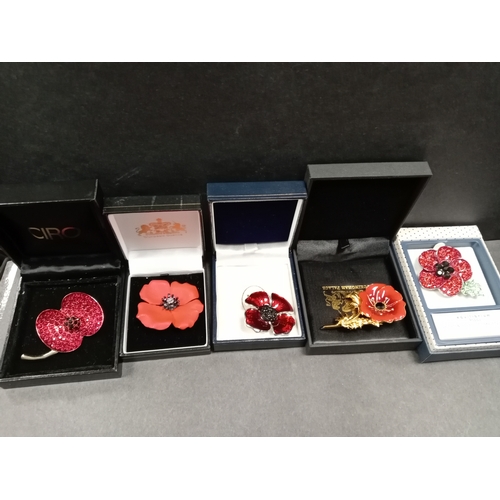 712 - Five boxed poppy brooches, one Buckingham Palace enamelled brooch, Equilibrium diamanté stone brooch... 