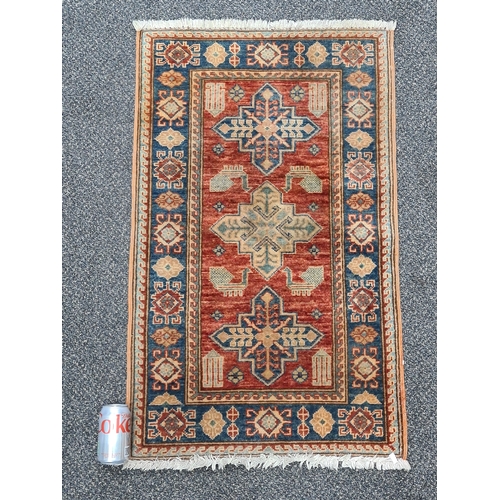 501 - Vintage Brick Red & Blue Patterned Persian/ Kazak Rug. Measures 100cm x 60cm.