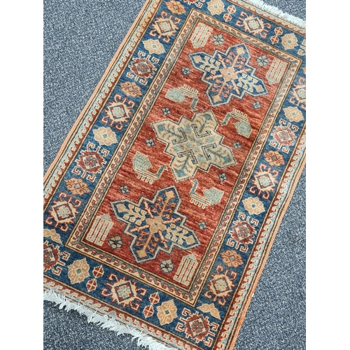 501 - Vintage Brick Red & Blue Patterned Persian/ Kazak Rug. Measures 100cm x 60cm.