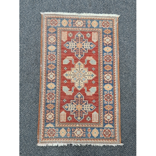 501 - Vintage Brick Red & Blue Patterned Persian/ Kazak Rug. Measures 100cm x 60cm.