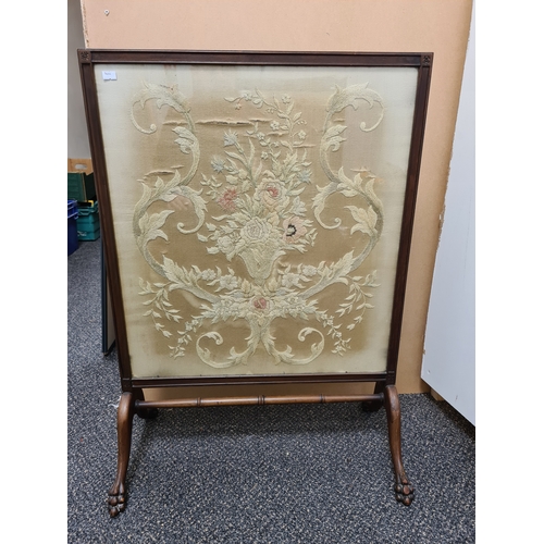 509 - Wooden fire screen guard with claw-foot feet and an embroidered floral pattern; Colours faded. Measu... 