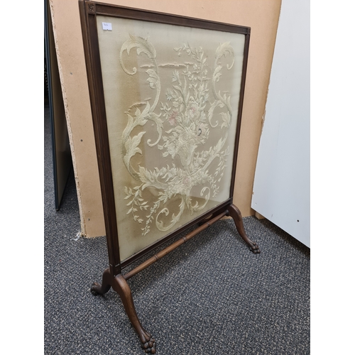 509 - Wooden fire screen guard with claw-foot feet and an embroidered floral pattern; Colours faded. Measu... 