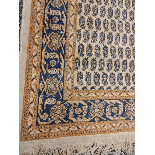 581 - A vintage paisley patterned silk rug with tassels. H 120cm x W 68cm