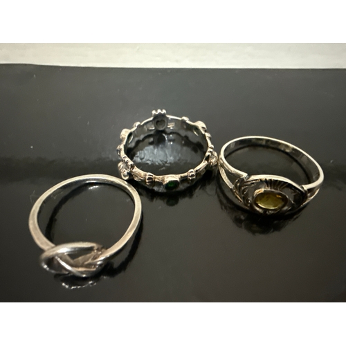 717 - 3 925 silver rings. One knot style, one with green stones and hearts and one with an amber coloured ... 