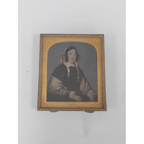 700 - An early 19th century danguerrotype of a woman in a brass frame with an ornate gold colour border an... 