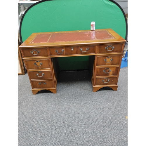 708 - A large red leather topped wooden desk with 9 drawers and original key, desk comes apart into 3 sect... 