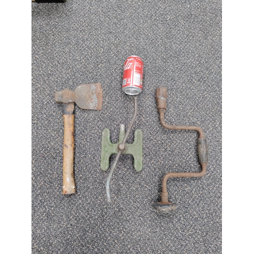 669 - A trio of vintage tools. To include a hand axe, hand drill and an aluminium sprinkler.