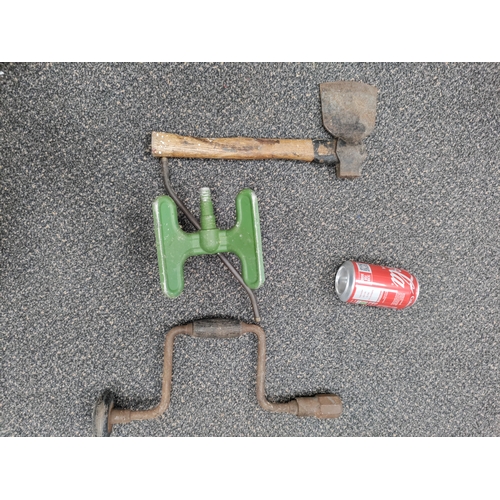 669 - A trio of vintage tools. To include a hand axe, hand drill and an aluminium sprinkler.