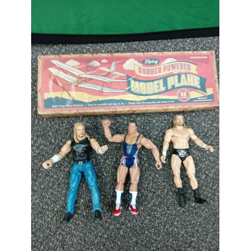 710 - Flying rubber powered model plane and three WWE figures, including Kurt Angle and Triple H.