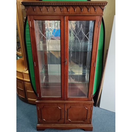 105 - A vintage wooden display cabinet with lighting and glass shelves. Includes keys.