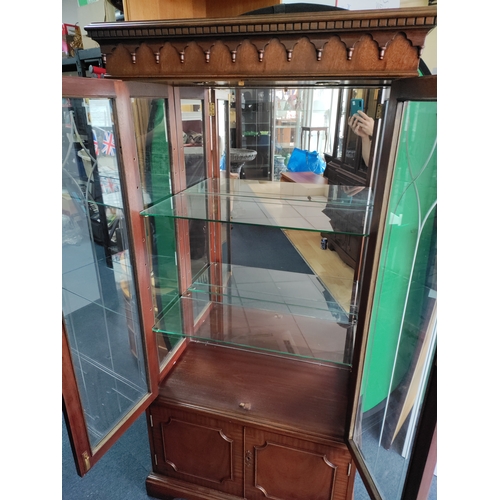105 - A vintage wooden display cabinet with lighting and glass shelves. Includes keys.