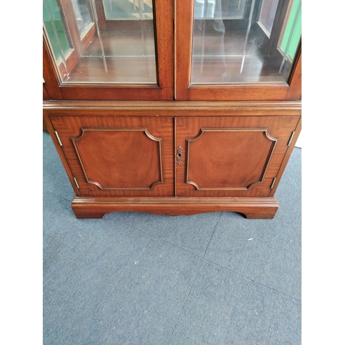 105 - A vintage wooden display cabinet with lighting and glass shelves. Includes keys.