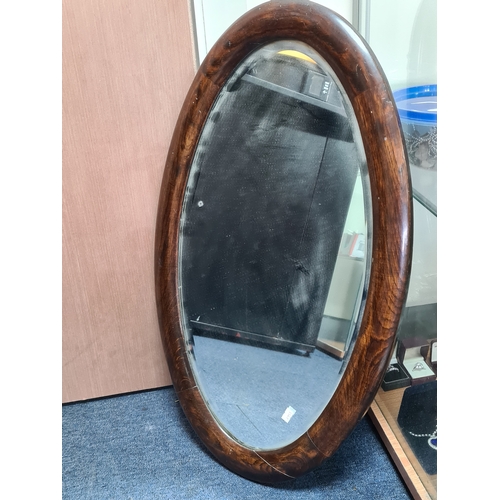 106 - Large vintage dark Oak oval mirror, measures H69cm x 41cm. AF