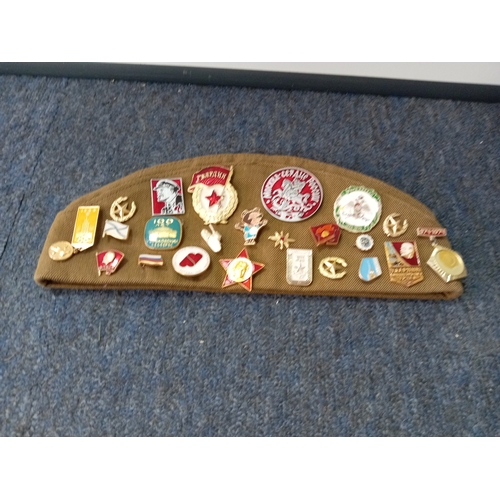 92 - A soviet military hat, possibly a budenovka or pilotka with various soviet era pins and badges.