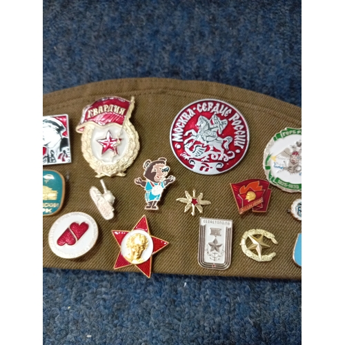 92 - A soviet military hat, possibly a budenovka or pilotka with various soviet era pins and badges.