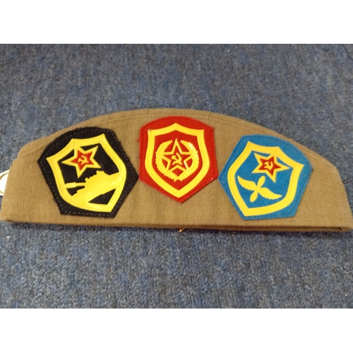 92 - A soviet military hat, possibly a budenovka or pilotka with various soviet era pins and badges.