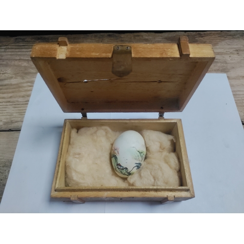 202 - A small wooden box housing a hand painted egg with Japanese lettering.