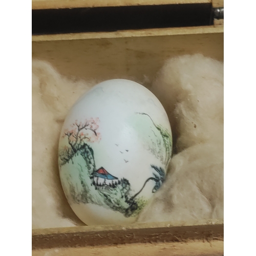 202 - A small wooden box housing a hand painted egg with Japanese lettering.