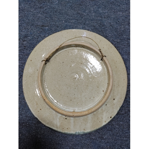 215 - A vintage Colin Kellam studio pottery wall plate decorated with a floral pattern. Diameter 28cm.