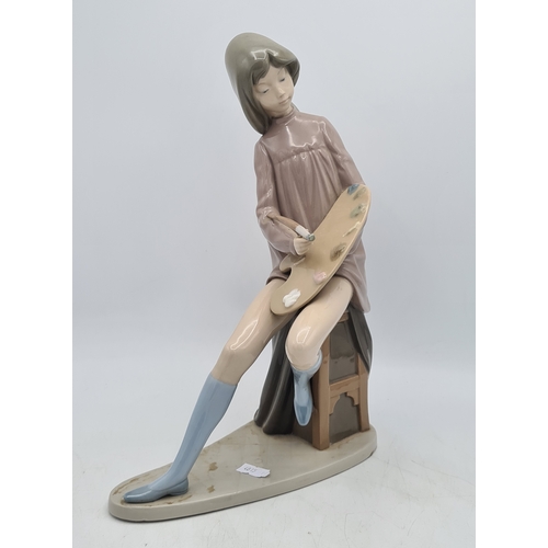 190 - Lladro Nao Porcelain Girl Artist Painter Figurine with palette. Measures 14cm high by 18cm wide.