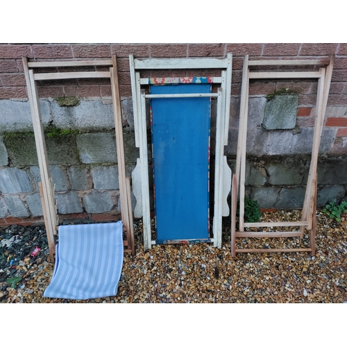 82 - A collection of three wooden deck chairs - two are just frames and the third features a floral desig... 