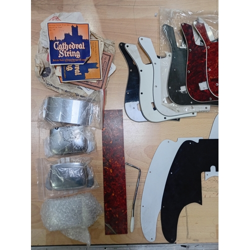 143 - A collection of vintage guitar stratch plates, strings, precision bass bridge, pickup covers and mor... 