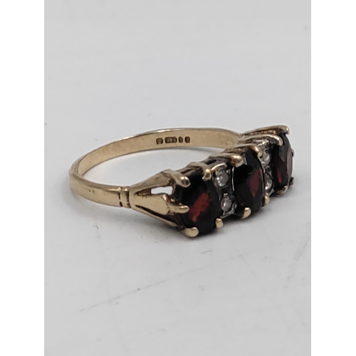 392 - A hallmarked 375 9ct gold ring set with garnets and diamonds. Size N.