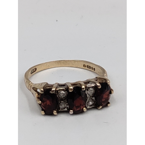 392 - A hallmarked 375 9ct gold ring set with garnets and diamonds. Size N.
