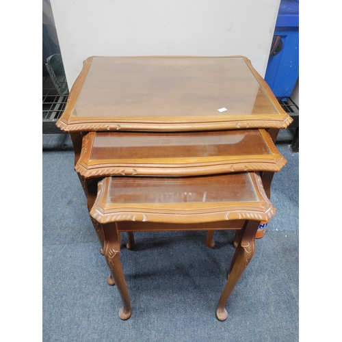 129 - A nest of tables with glass tops. Largest measurements are 55cm x 54cm x 42cm.