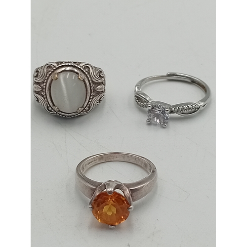 395 - A hallmarked 925 silver ring set with an orange stone and two costume rings.