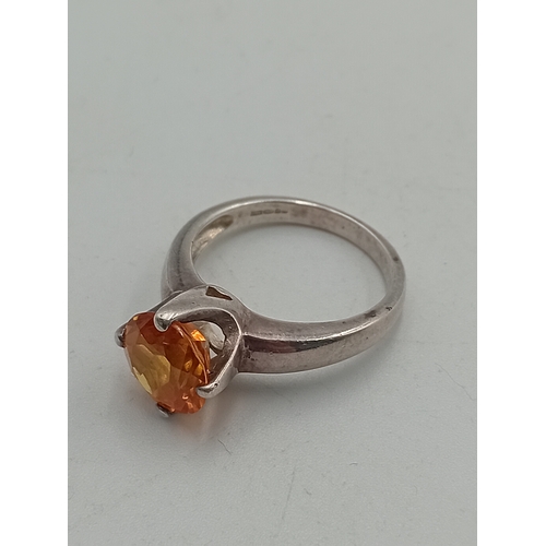 395 - A hallmarked 925 silver ring set with an orange stone and two costume rings.