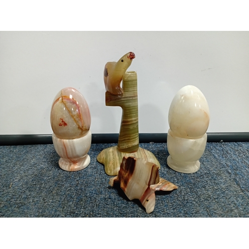27 - A collection of hardstone ornaments including a plane, eggs and eggcups, birds, togrther with a glas... 