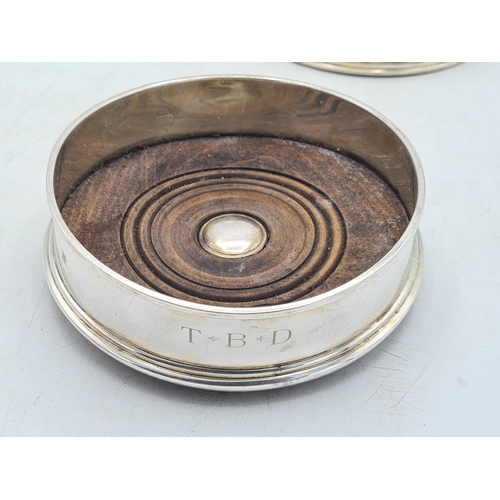 258 - 2 Sterling Silver & Oak Bottle Coasters. One is engraved T.B.D. Each measures 12.5cm in diameter by ... 