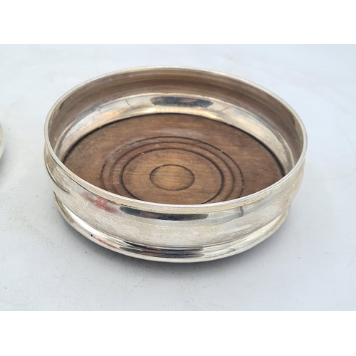 258 - 2 Sterling Silver & Oak Bottle Coasters. One is engraved T.B.D. Each measures 12.5cm in diameter by ... 